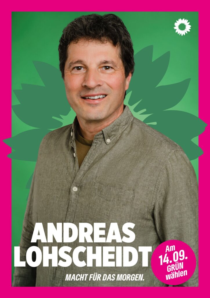 Portraitaufnahme von Andreas Lohscheidt als Wahlplakat mit grüner Sonnenblume im Hintergrund, weißer kleiner Sonnenblume oben rechts, seinem Namen, einem Button mit dem Text "Am 14.09. Grün wählen" und dem Claim Macht für das Morgen.