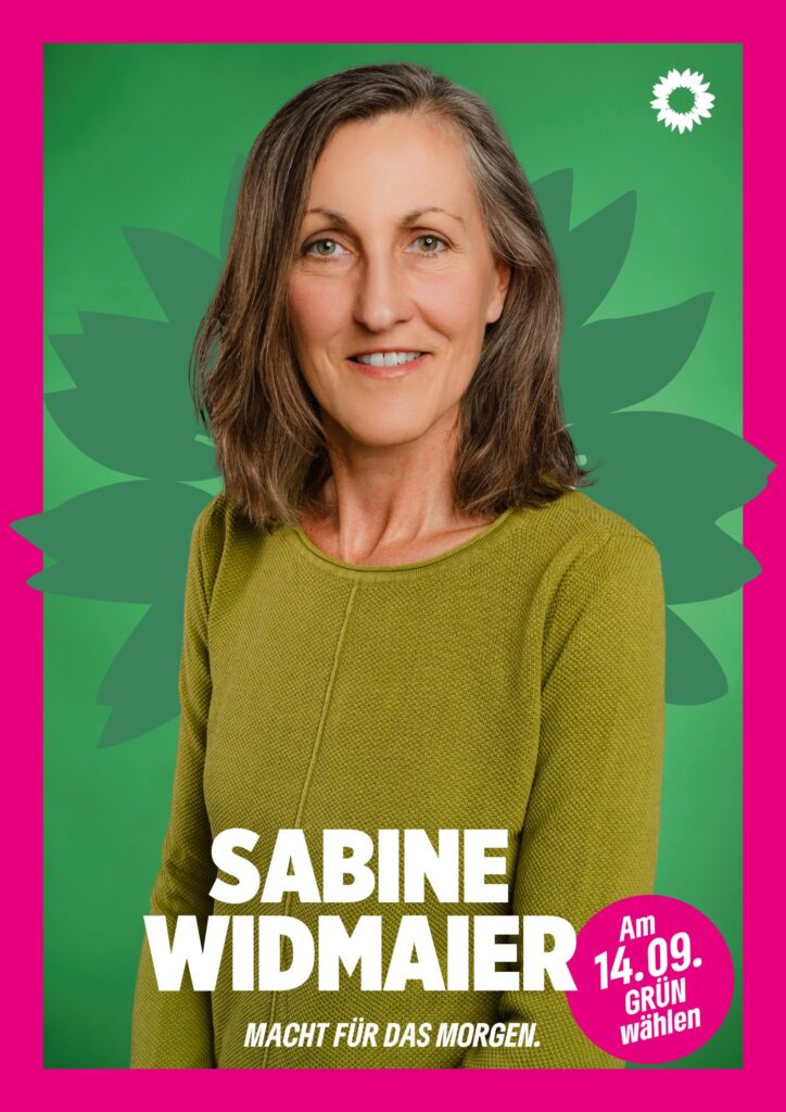 Portraitaufnahme von Sabine Widmaier als Wahlplakat mit grüner Sonnenblume im Hintergrund, weißer kleiner Sonnenblume oben rechts, seinem Namen, einem Button mit dem Text "Am 14.09. Grün wählen" und dem Claim Macht für das Morgen.