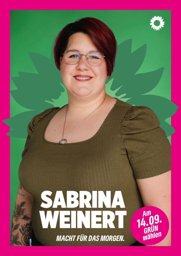 Portraitaufnahme von Sabrina Weinert als Wahlplakat mit grüner Sonnenblume im Hintergrund, weißer kleiner Sonnenblume oben rechts, seinem Namen, einem Button mit dem Text "Am 14.09. Grün wählen" und dem Claim Macht für das Morgen.