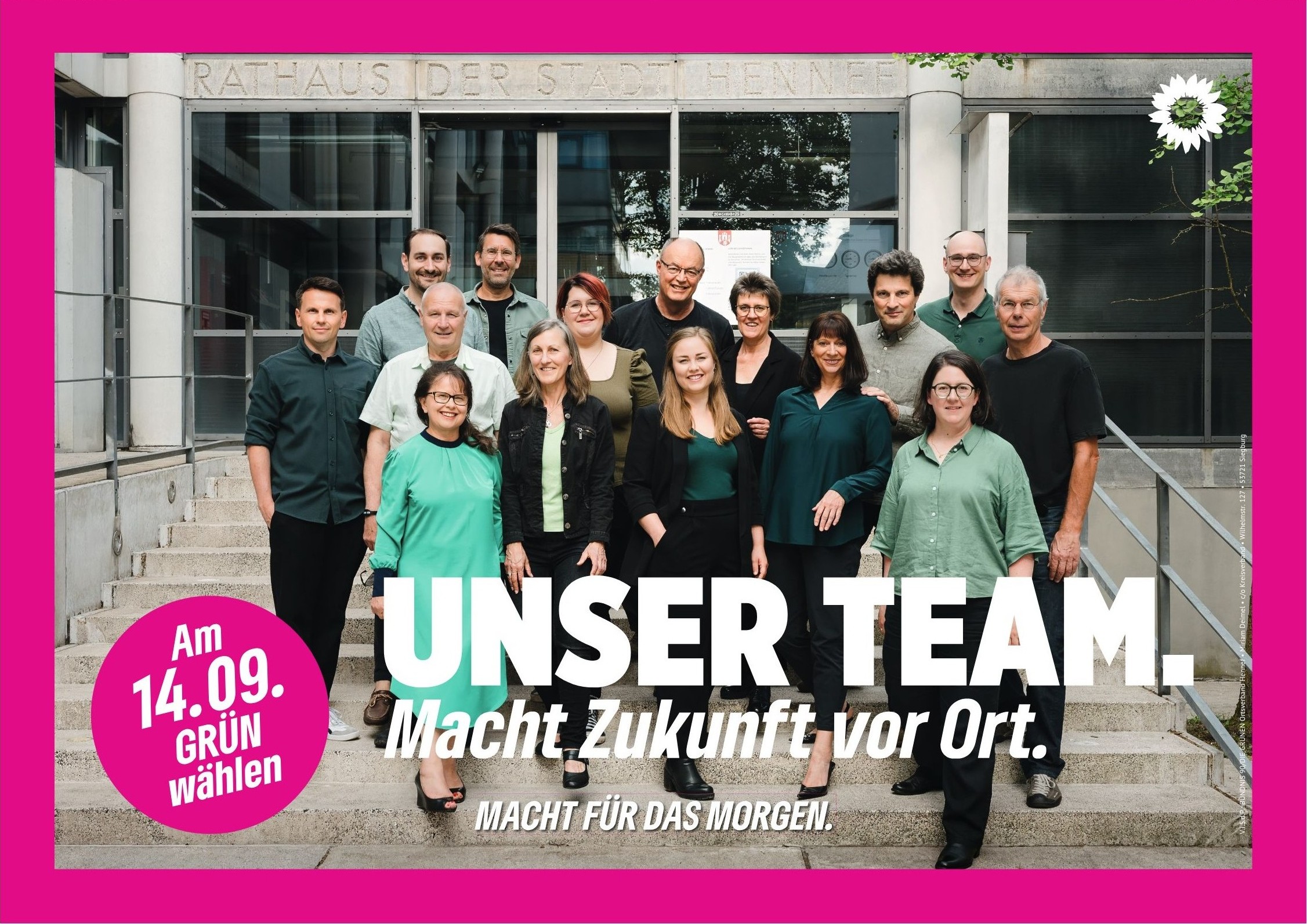 Wahlplakat mit pinkem Rand mit 15 Personen auf einer Treppe vor dem Rathaus der Stadt Hennef und dem Slogan Unser Team. Macht Zukunft vor Ort. und dem Claim ganz unten Macht für das Morgen. Unten links einen pinken Kreis mit dem Slogan "Am 14.09. GRÜN wählen"